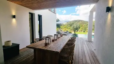 a wooden table on a deck with a view of the water at Villa Juca, 10 pers, piscine chauffée, 10 minutes plage in Cirendinu
