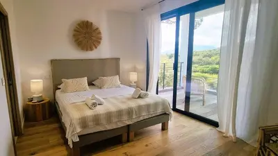 a bedroom with a bed with a view of a balcony at Villa Juca, 10 pers, piscine chauffée, 10 minutes plage in Cirendinu