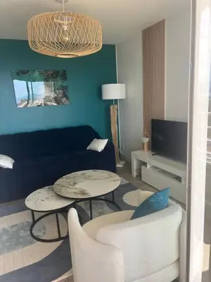 a living room with a couch and tables and a tv at Bleu Corse, entre mer et soleil in Ajaccio