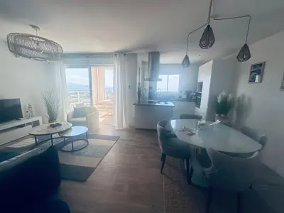 a living room with a table and a kitchen at Bleu Corse, entre mer et soleil in Ajaccio