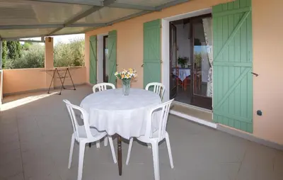 a table with white chairs and a vase of flowers on a patio at Appartement Residence Piscine in Venzolasca