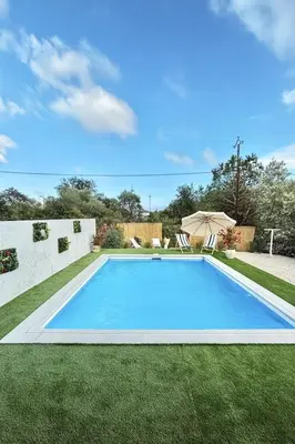 a blue swimming pool in a yard with grass at Maison Dolce Vita in Ghisonaccia
