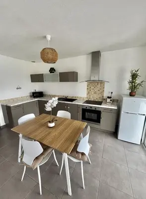 a kitchen with a wooden table and white chairs at Maison Dolce Vita in Ghisonaccia