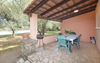 a patio with a table and chairs and a fireplace at Maison Residence Piscine in Venzolasca