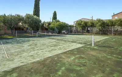 a tennis court with a net on a field at Maison Residence Piscine in Venzolasca