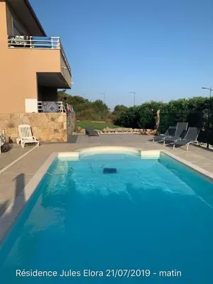 a large blue swimming pool next to a building at T3 - bord de mer - piscine - vue magnifique in Propriano