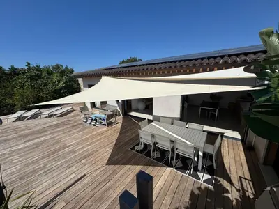 a patio with tables and chairs under a white umbrella at VILLA Corse du Sud in Pianottoli-Caldarello
