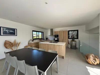 a kitchen with a black table and white chairs at VILLA Corse du Sud in Pianottoli-Caldarello