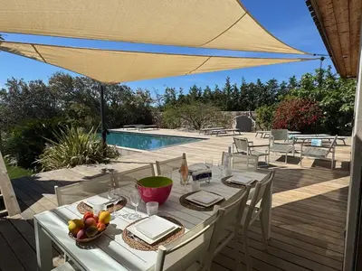 a white table with a bowl of fruit and an umbrella at VILLA Corse du Sud in Pianottoli-Caldarello