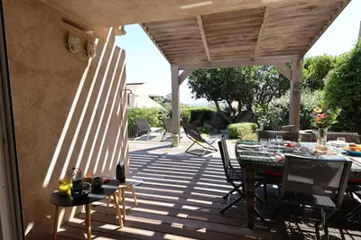 a patio with a table and chairs on a deck at Villa U Serenu - Piscine, Jacuzzi & Vue Mer in Bonifacio