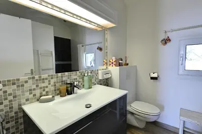 a bathroom with a sink and a toilet and a mirror at Villa U Serenu - Piscine, Jacuzzi & Vue Mer in Bonifacio