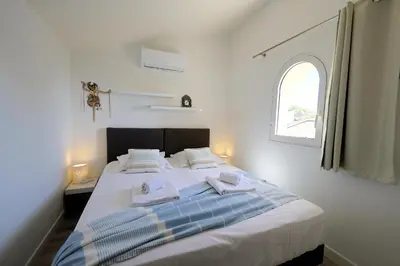 a white bedroom with a bed with towels on it at Villa U Serenu - Piscine, Jacuzzi & Vue Mer in Bonifacio