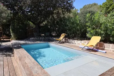 a swimming pool with two chairs and a table at Villa U Serenu - Piscine, Jacuzzi & Vue Mer in Bonifacio