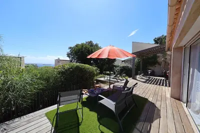 a woman sitting in a chair under an umbrella on a deck at Villa U Serenu - Piscine, Jacuzzi & Vue Mer in Bonifacio