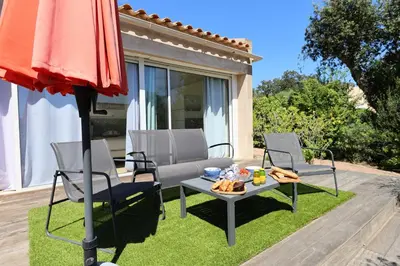 a patio with two chairs and a table and an umbrella at Villa U Serenu - Piscine, Jacuzzi & Vue Mer in Bonifacio