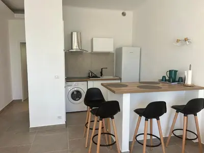 a kitchen with a counter and four stools at Bel appartement pied dans l'eau PROPRIANO in Propriano