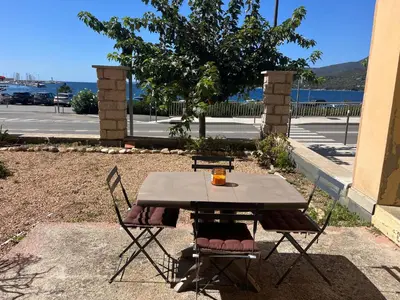 a table with two chairs and a drink on it at Bel appartement pied dans l'eau PROPRIANO in Propriano