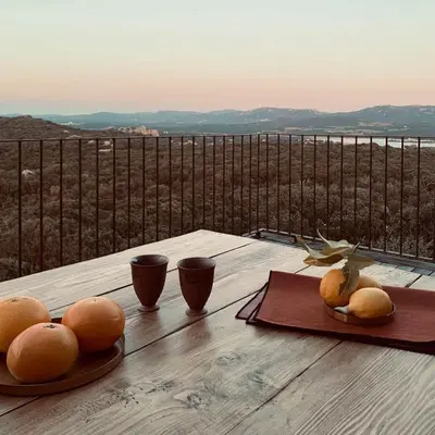 a table with oranges and cups on a table with a view at Lenza Barn Villa by Boutique Scenic Corsica in Pianottoli-Caldarello