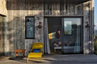 a house with a yellow chair and a bedroom at Lenza Barn Villa by Boutique Scenic Corsica in Pianottoli-Caldarello