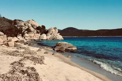 a beach with rocks and blue water and the ocean at Lenza Barn Villa by Boutique Scenic Corsica in Pianottoli-Caldarello