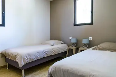 a room with two beds and two tables with lamps at Entre mer et montagne Villa Cartalavonu in Porto-Vecchio