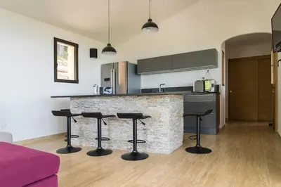 a kitchen with two bar stools and a counter at Entre mer et montagne Villa Cartalavonu in Porto-Vecchio