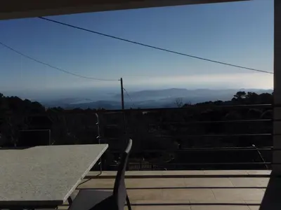 a table and chair on a balcony with a view at Entre mer et montagne Villa Cartalavonu in Porto-Vecchio