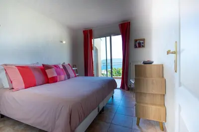 a bedroom with a bed with pink and purple pillows at Villa de Charme avec Piscine et vue Mer en Corse du Sud in Propriano