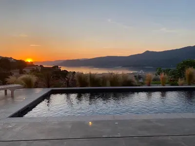 a swimming pool with a sunset in the background at Villa de Charme avec Piscine et vue Mer en Corse du Sud in Propriano