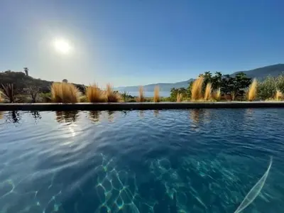 a large pool of water with the sun in the background at Villa de Charme avec Piscine et vue Mer en Corse du Sud in Propriano