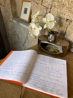 an open book on a table with a vase of flowers at Villa de Charme avec Piscine et vue Mer en Corse du Sud in Propriano