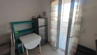 a kitchen with a refrigerator and a chair next to a window at Moriani-Plage 1-bedroom apartment in San-Nicolao