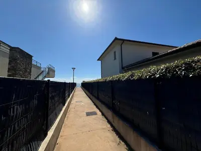 a fence next to a sidewalk next to a building at Moriani-Plage in Santa-Lucia-di-Moriani