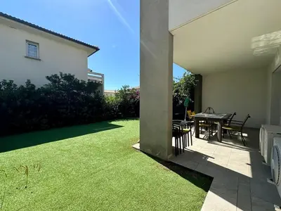 a patio with a table and a lawn at Moriani-Plage in Santa-Lucia-di-Moriani
