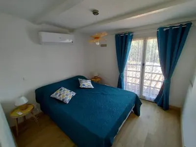a bedroom with a blue bed and a window at Villa bord de mer Résidence Alba Serena in Poggio-Mezzana