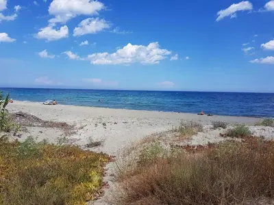 a beach with people laying on the sand and the ocean at Villa bord de mer Résidence Alba Serena in Poggio-Mezzana