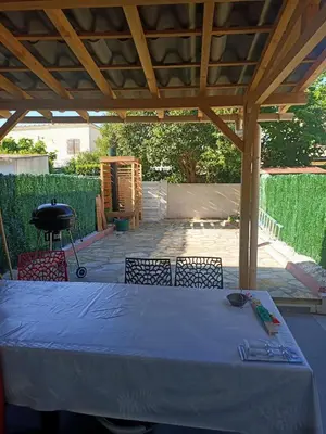 a table and chairs under a wooden pergola at Villa bord de mer Résidence Alba Serena in Poggio-Mezzana