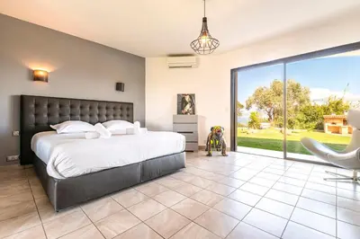 a bedroom with a bed and a sliding glass door at Villa Aigue Marine - Front de mer in Coti-Chiavari