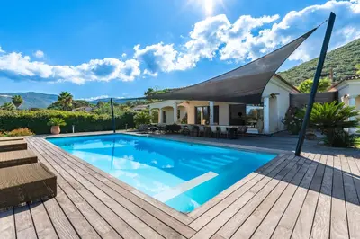 a swimming pool on a wooden deck next to a house at Villa Aigue Marine - Front de mer in Coti-Chiavari