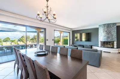 a dining room with a long table and a fireplace at Villa Aigue Marine - Front de mer in Coti-Chiavari
