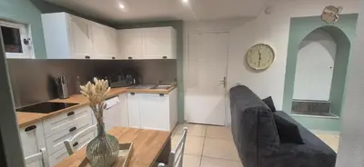 a kitchen with a table with chairs and a refrigerator at Appartement cosy vue mer in Grosseto-Prugna