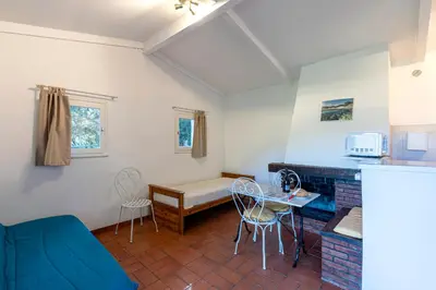 a living room with a bed and a table and chairs at Villa F2 Tonnara pour 4 personnes, Rondinara, Bonifacio in Bonifacio
