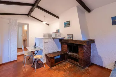 a living room with a fireplace and a table and chairs at Villa F2 Tonnara pour 4 personnes, Rondinara, Bonifacio in Bonifacio