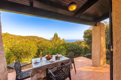 a table on a patio with a view of the ocean at Villa F2 Tonnara pour 4 personnes, Rondinara, Bonifacio in Bonifacio