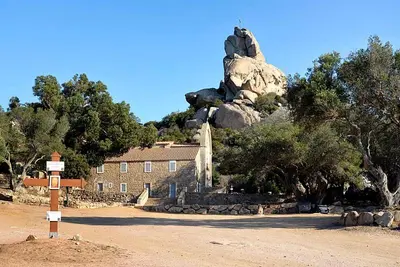 a building in front of a mountain with a rock at Logement dans terrain privé et familiale in Bonifacio