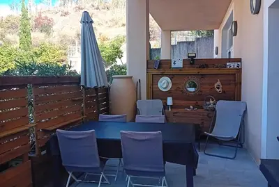 a patio with a table and chairs and an umbrella at T3 Bord de mer Agosta plage in Albitreccia