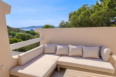 a white couch on a balcony with a view of the ocean at Casetta Mare di Cala Rossa in Cala Rossa