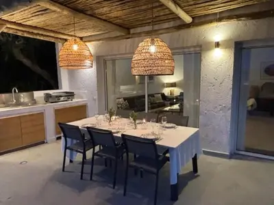 a dining room table with chairs and a kitchen at Villa 8 pers vue180 golfe de Porto Vecchio in Porto-Vecchio