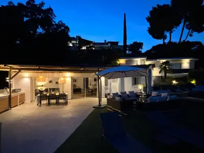 a patio with chairs and an umbrella at night at Villa 8 pers vue180 golfe de Porto Vecchio in Porto-Vecchio