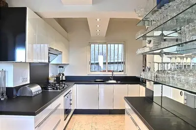a large kitchen with white cabinets and black counter tops at Villa 8 pers vue180 golfe de Porto Vecchio in Porto-Vecchio